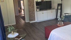 A hotel room with a bed, a TV, a desk, and a seating area. - Unit 17 King suite kitchen Fast Wifi Smart TV (Hot Springs)
