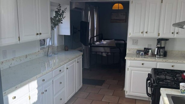 A kitchen with white cabinets, a central island, a stove, and a dining area with a table and chairs. - Unit 17 King suite kitchen Fast Wifi Smart TV (Hot Springs)