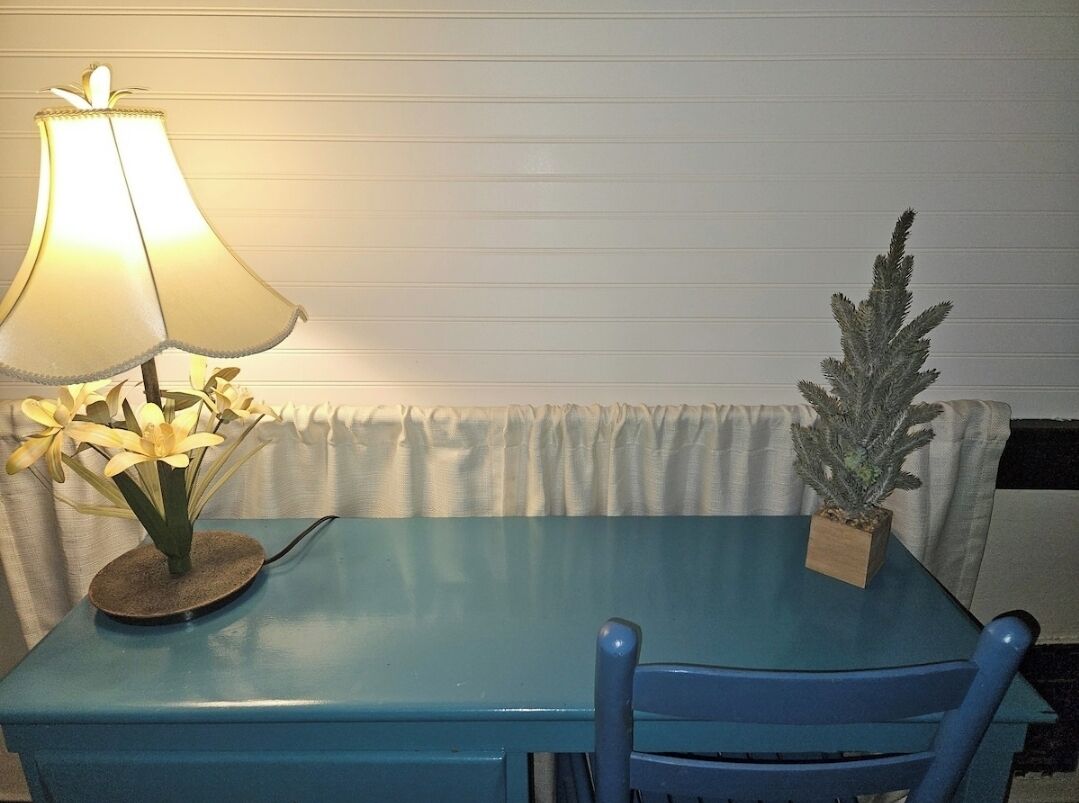 Une table bleue avec une lampe et une plante en pot.