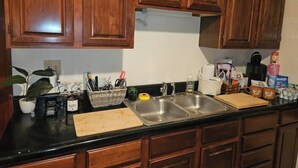 A kitchen with wooden cabinets, a black countertop, a double sink, and various kitchen items. - Charming 2-bedroom, cozy bungalow with sunroom in fabulous St. Louis with WiFi (St. Louis)
