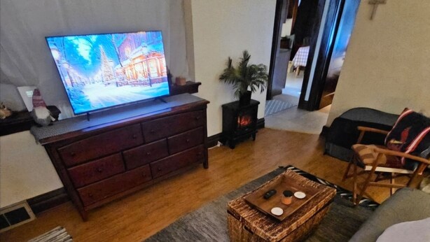 A living room with a TV, wooden furniture, a fireplace, and a cozy seating area. - Charming 2-bedroom, cozy bungalow with sunroom in fabulous St. Louis with WiFi (St. Louis)