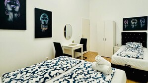 A hotel room with two beds, a desk, a chair, a mirror, and artwork on the walls.