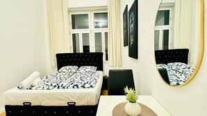 A bedroom with a bed, a bedside table with a plant, a chair, and a mirror on the wall.