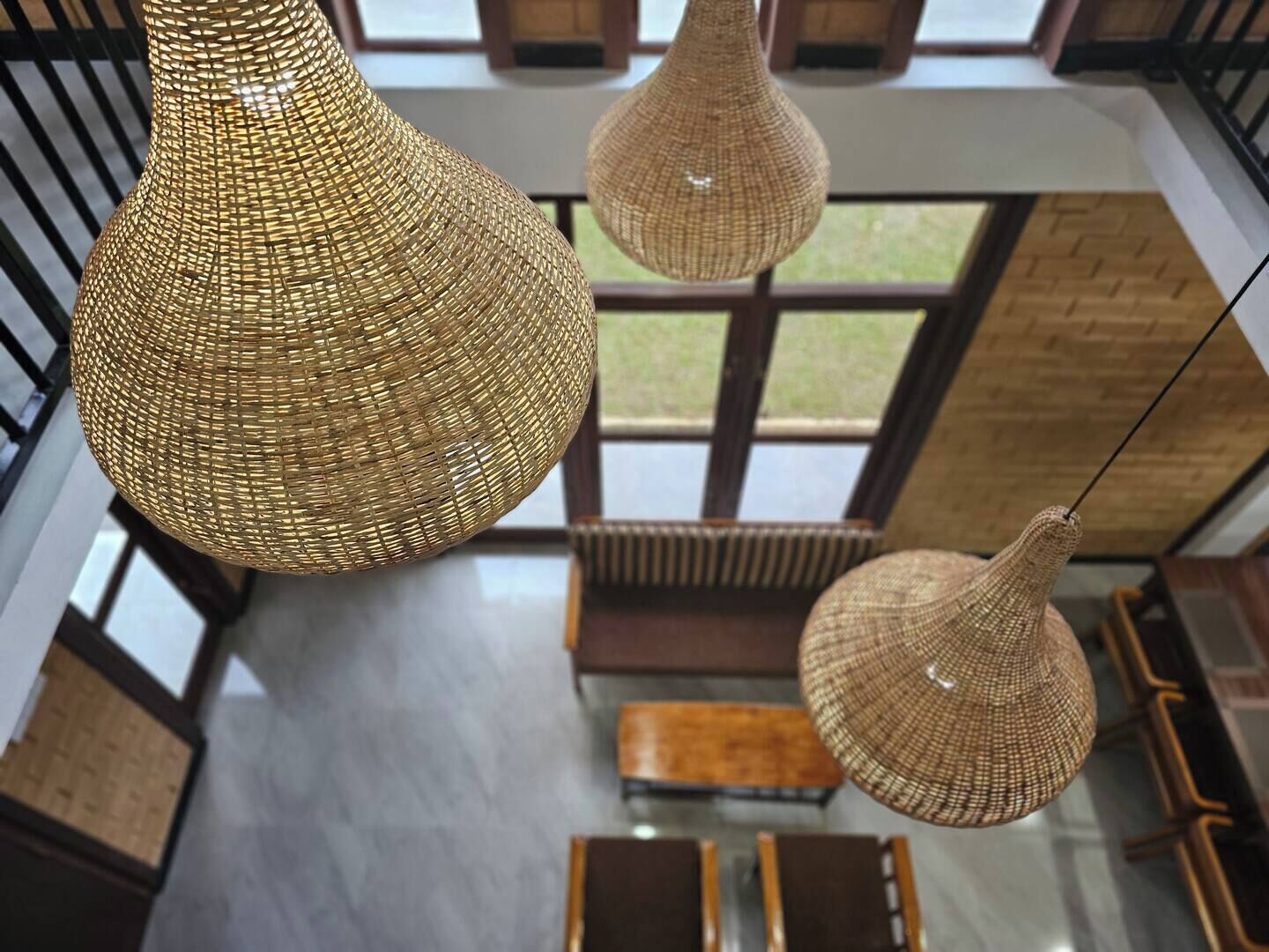 Een ruim interieur met hoge plafonds, grote ramen en hangende geweven lampen.