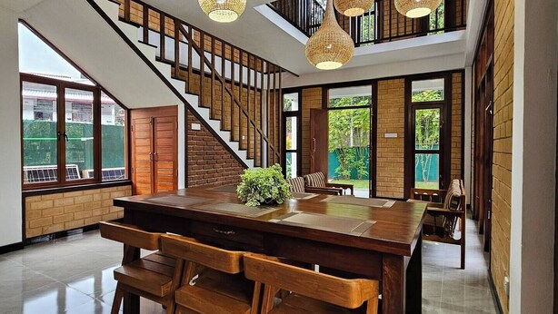 A spacious dining area with a large wooden table and benches, a staircase leading to an upper level, and hanging wicker pendant lights. - Seagulls Garden -450 m to beach & Free* Utility (Hikkaduwa)