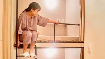 A person sitting on a bunk bed in a room with a simple, functional design.