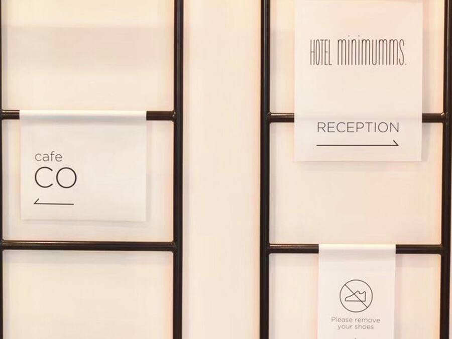 Un mur orné de panneaux encadrés indiquant les services offerts par l’hôtel, tels qu’un café, une réception et les règles concernant le retrait des chaussures.