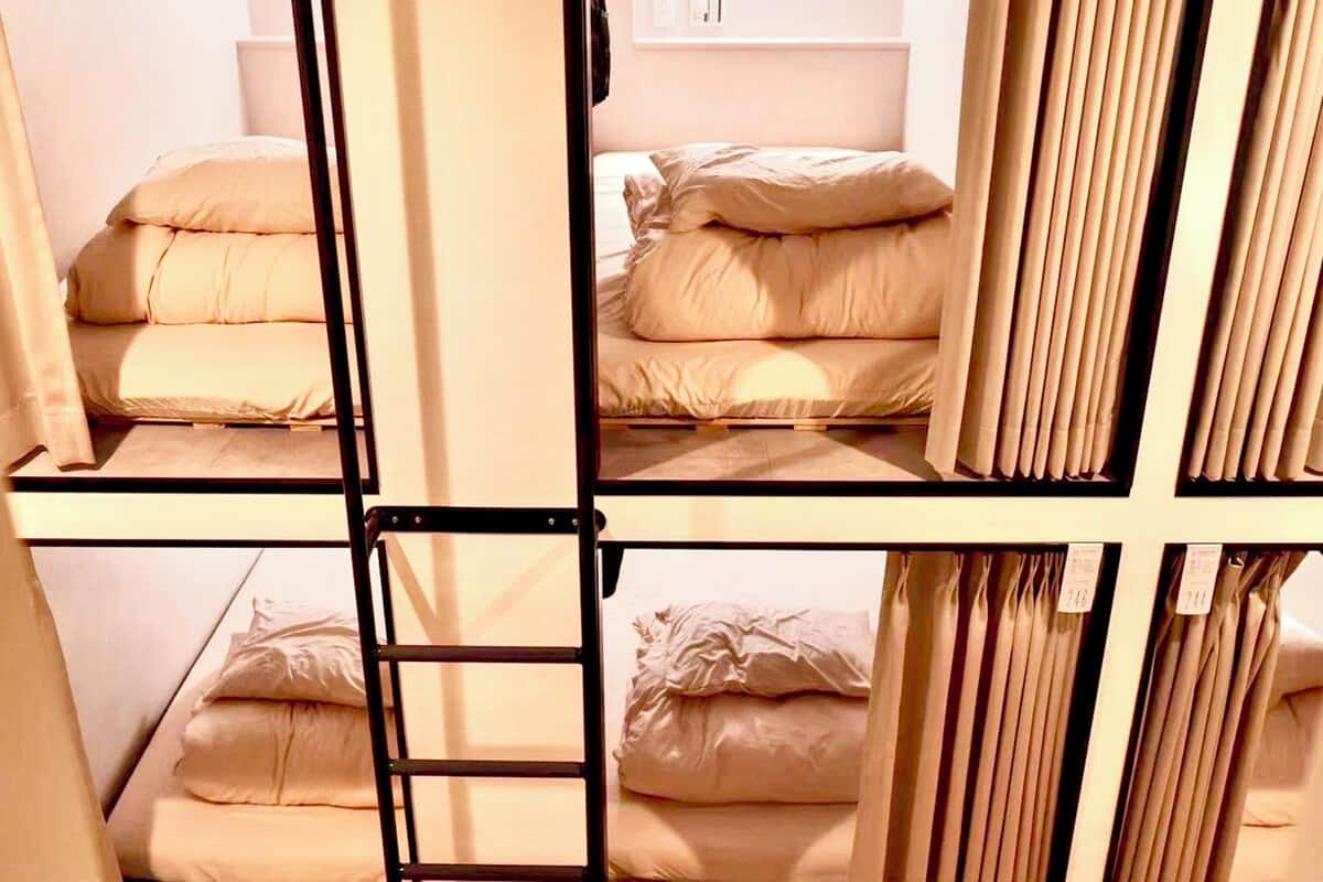 A bunk bed room with a ladder, a wall-mounted light, and a curtain.