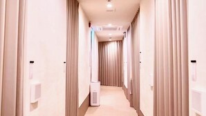 Ein Hotelgang mit einer zentralen Klimaanlage, einem an der Wand befestigten Desinfektionsmittelspender und einer Deckenleuchte.