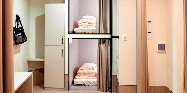 Um quarto com uma cama, um guarda-roupa e uma pequena mesa.