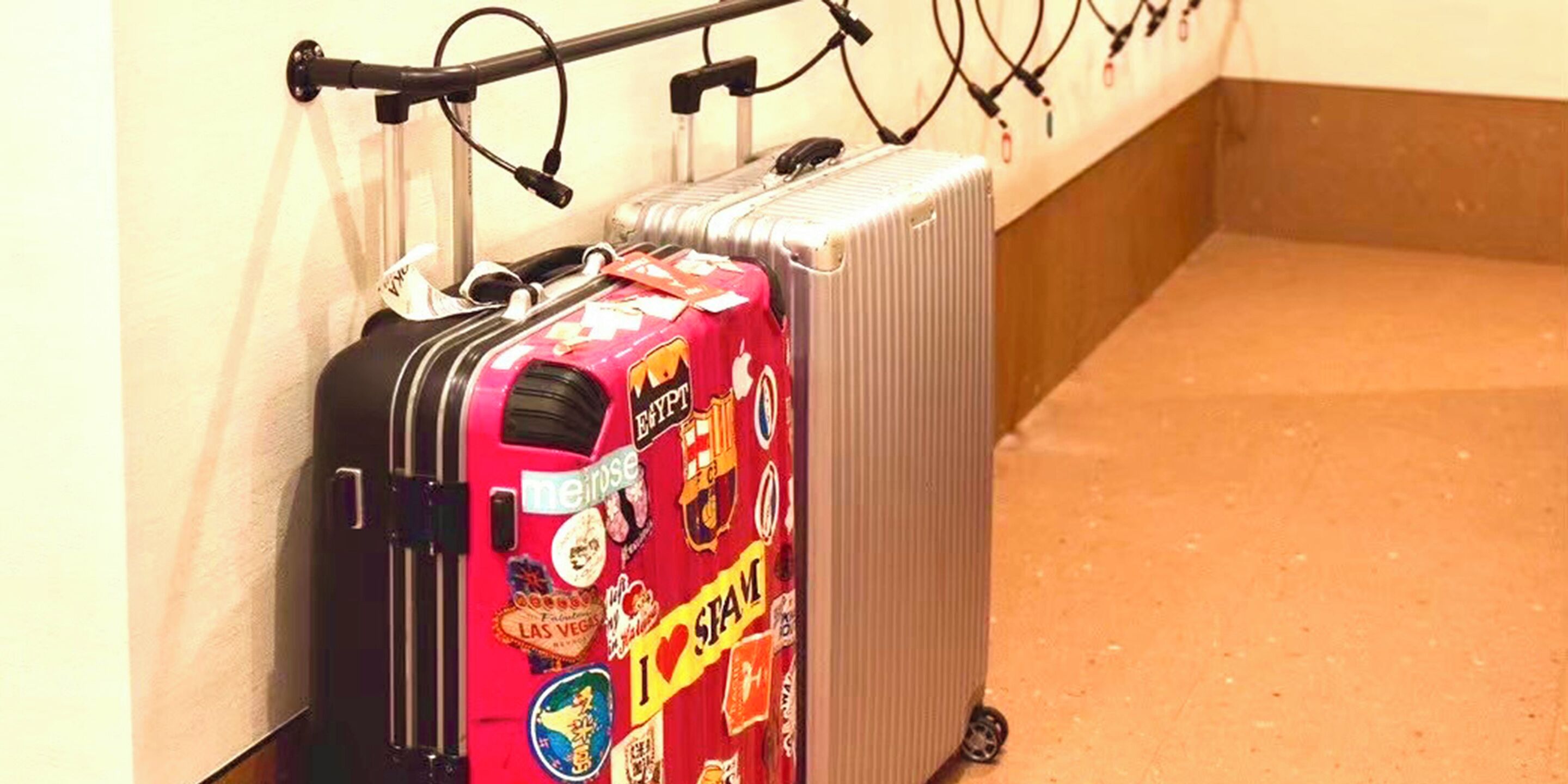Een rode koffer met verschillende stickers en een zilveren radiator ernaast.