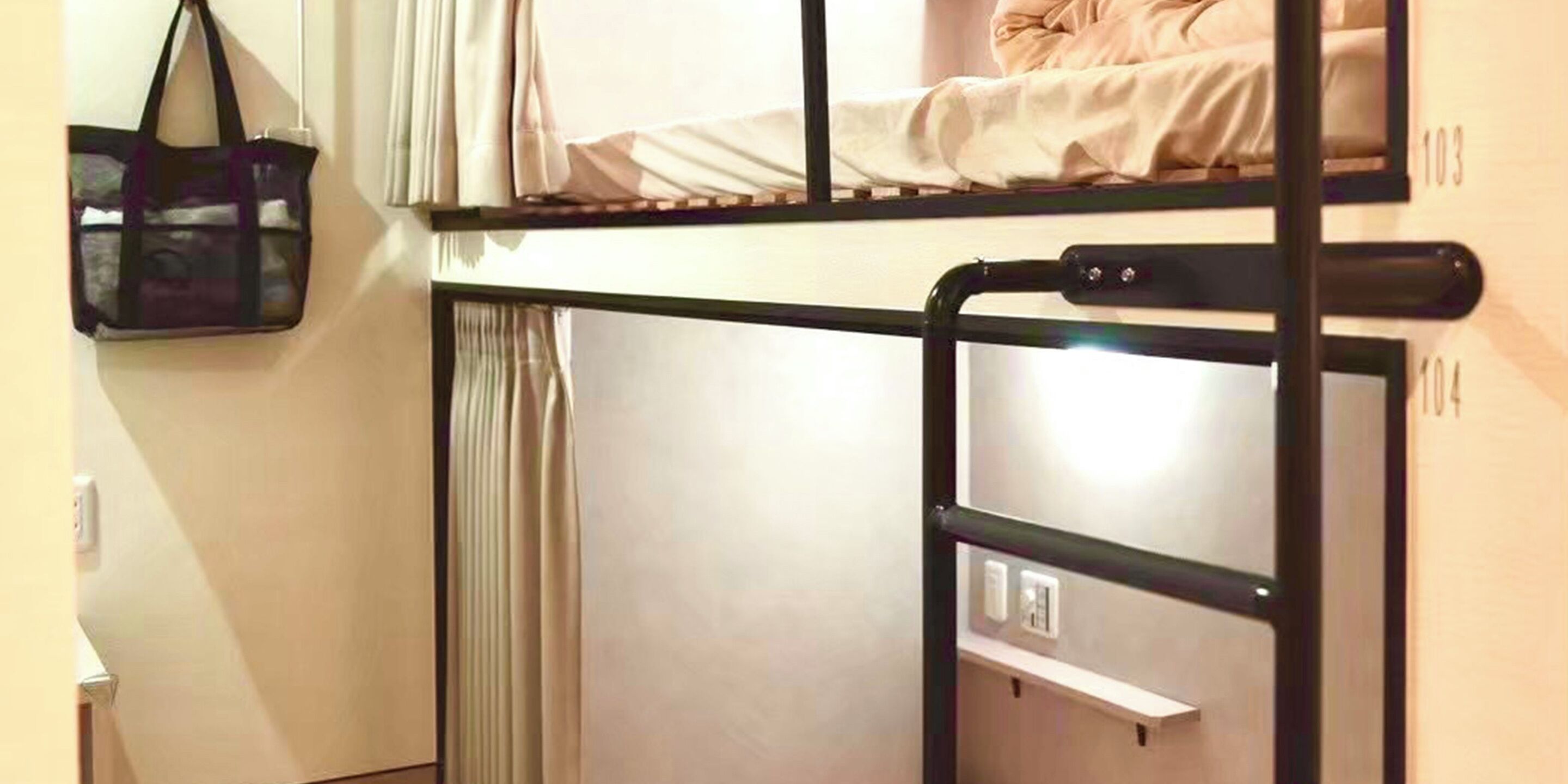 A bunk bed with a ladder, a hanging bag, and a window with curtains.