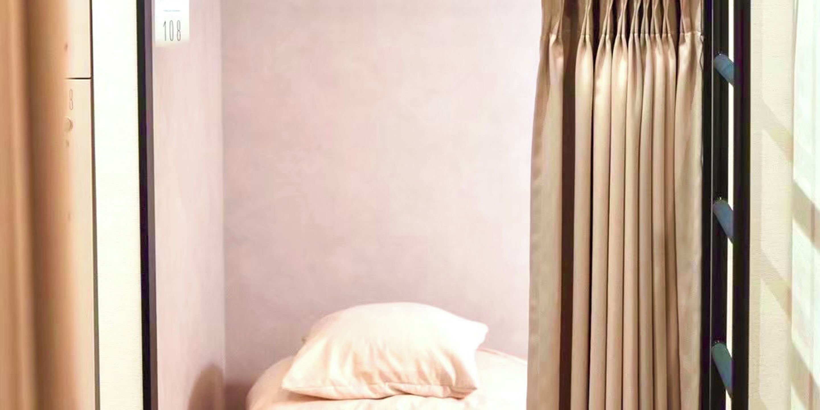 A room with a bed, a window with curtains, and a wall with a number sign.