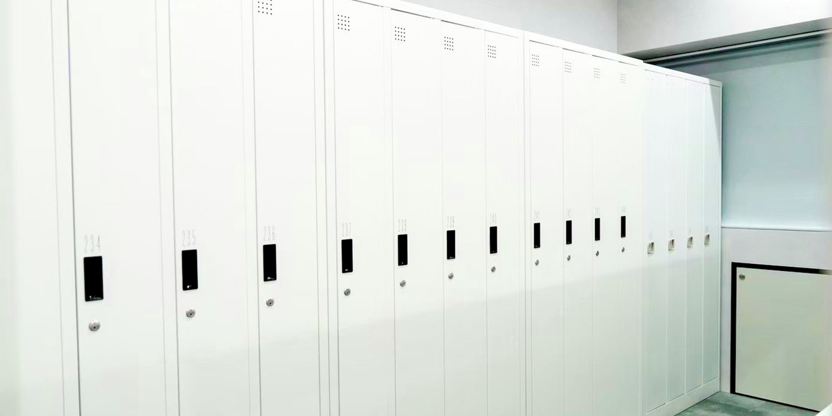 A row of white lockers with numbered doors, likely in a hotel or similar facility.