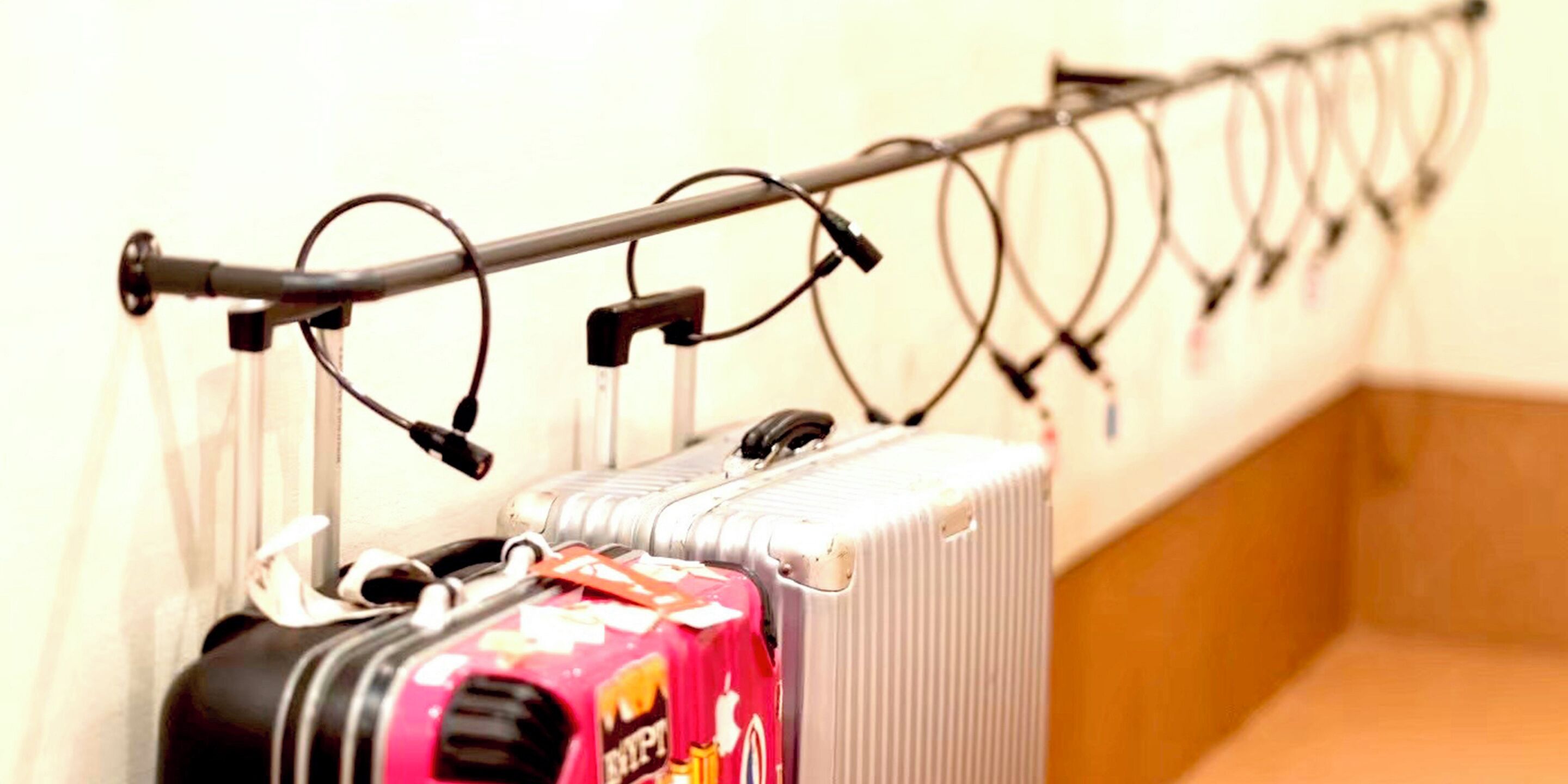 A row of suitcases on a wall-mounted rack in a hotel room.