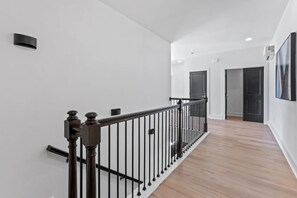 A modern interior with a wooden floor, a black metal railing, and white walls. - The Retreat - South of the River (Fosters)
