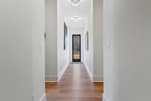 A hallway with wooden flooring, white walls, and a door at the end. - The Retreat - South of the River (Fosters)