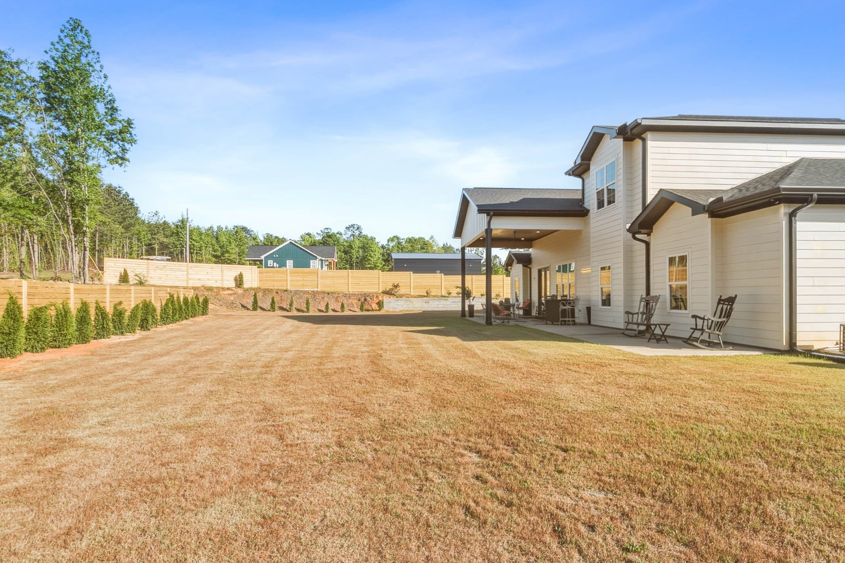 A residential property with a covered patio area, a fenced yard, and a house with a garage.