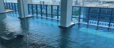 An infinity pool with a view of a cityscape, including high-rise buildings and a body of water.