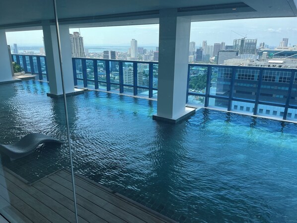 An infinity pool with a view of a cityscape, including high-rise buildings and a body of water.