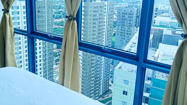 A hotel room with a large window offering a view of a cityscape. - Luxurious 2-BR, 2-BA, 34th Flr, 38 Park Avenue (Cebu City)