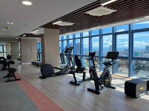 A modern gym with cardio machines, weight benches, and a red carpet.