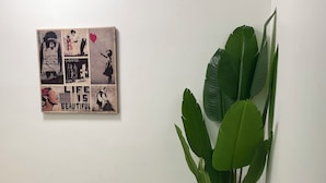 A bench and a potted plant against a wall with a piece of artwork. - Need a dose of Vitamin Sea? (Elwood)