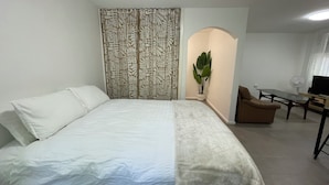 A hotel room with a bed, a desk, a chair, a potted plant, and a television. - Need a dose of Vitamin Sea? (Elwood)