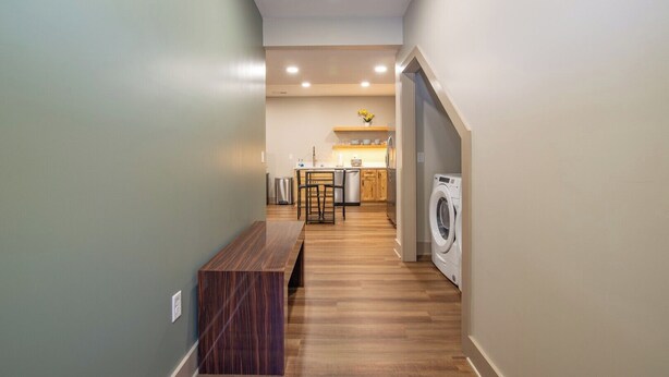 A modern kitchen with wooden flooring, a bench, and a washing machine. - The E-town Hideaway (Elizabethtown)