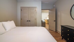 A bedroom with a bed, a dresser, and a door leading to a bathroom. - The E-town Hideaway (Elizabethtown)