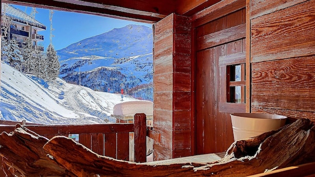 Una cabaña de madera con vista a un paisaje montañoso nevado.