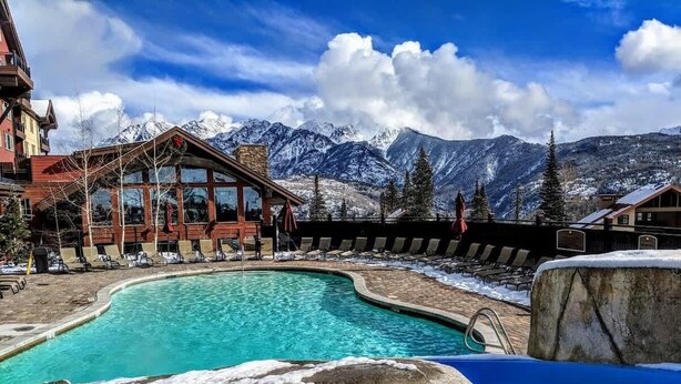 A pool area with lounge chairs and a building with large windows. - Mountain view Durango ski-in/out@ Purgatory Resort (Durango)