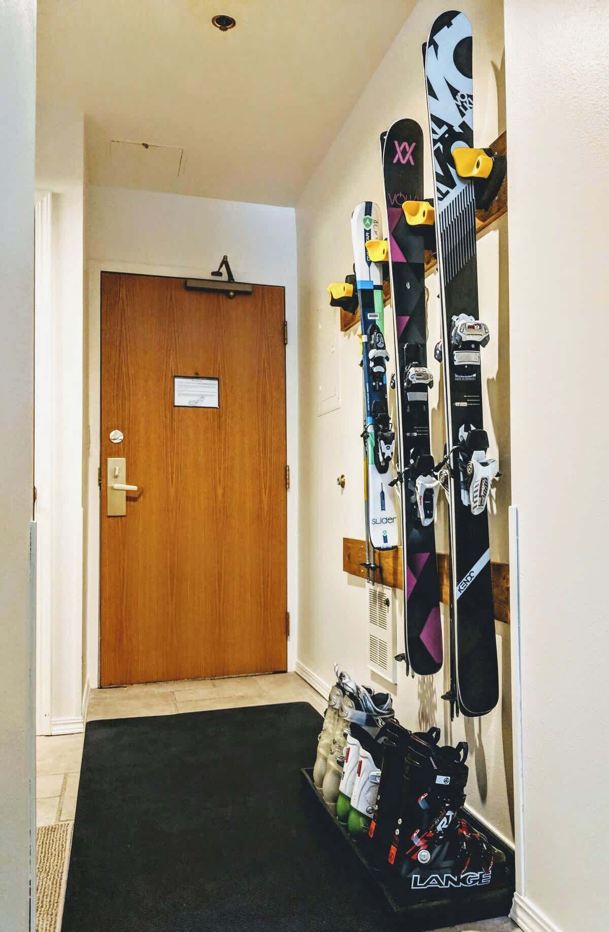 A hallway with a wooden door, skis, and ski equipment on the wall.