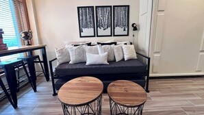 A living room with a dark sofa, two round wooden tables, a dining table with chairs, and three framed pictures on the wall. - Mountain view Durango ski-in/out@ Purgatory Resort (Durango)