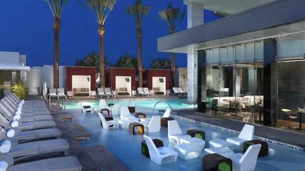 A pool area with lounge chairs and a glass-enclosed bar area.