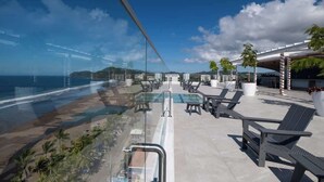 Zona de piscina al terrat amb gandules i vista a l'oceà.