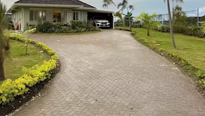 Ein Haus mit Garage, befestigter Auffahrt und gepflegtem Rasen mit Palmen.