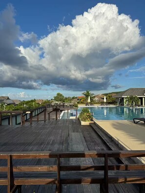 A wooden deck with a pool and lounge chairs, overlooking a residential area with houses and a clear sky. - Hillcrest Heaven Elegant Escape in Richmond Estate, St. Ann with Private Beach (Priory)