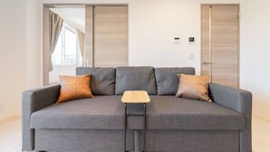 Un canapé gris avec quatre coussins, une petite table en bois et, au fond, une porte coulissante.