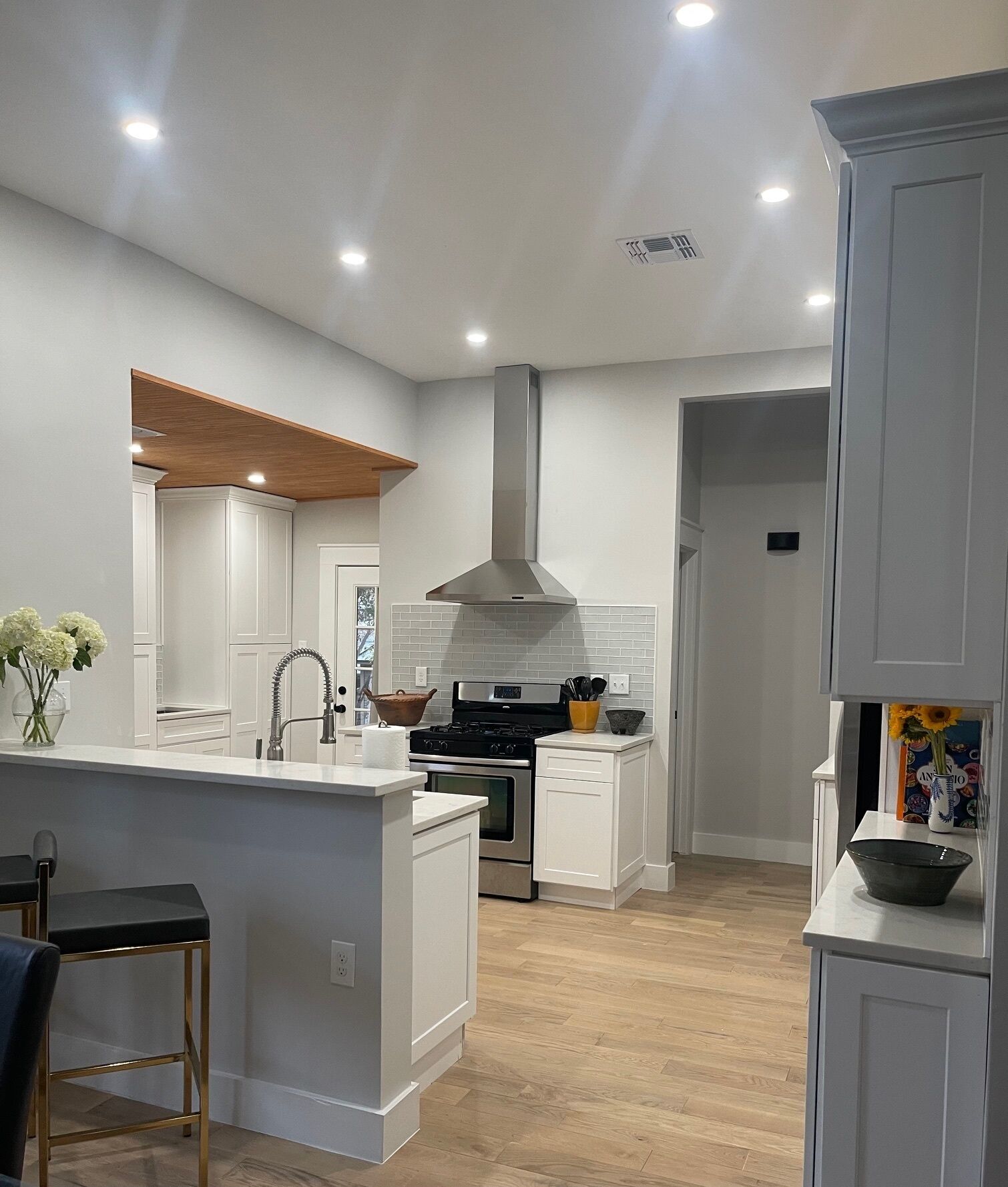 Een moderne keuken met witte kasten, een centraal eiland en een houten plafonddetail.