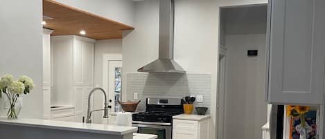 Una cocina moderna con armarios blancos, una isla central y un detalle de techo de madera.