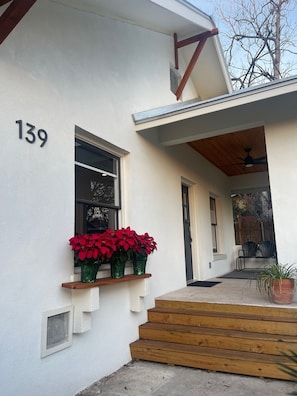 A house with the number 139 on the wall, a wooden staircase, and a window with red poinsettias. - A guest favorite! Charming 2-bedroom house- stylish comfort in a great area (San Antonio)