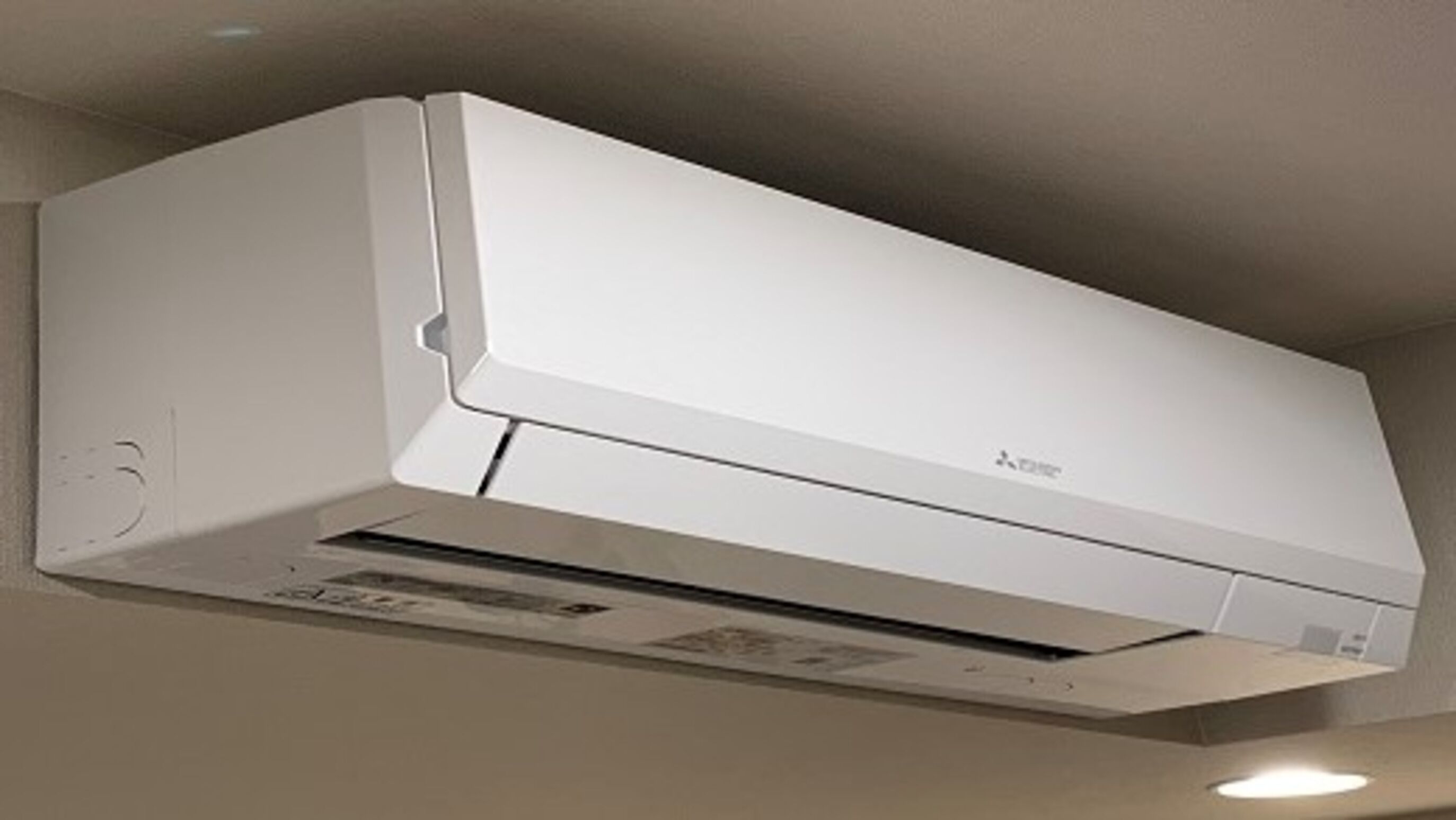 A white wall-mounted air conditioning unit with a control panel and a filter compartment.
