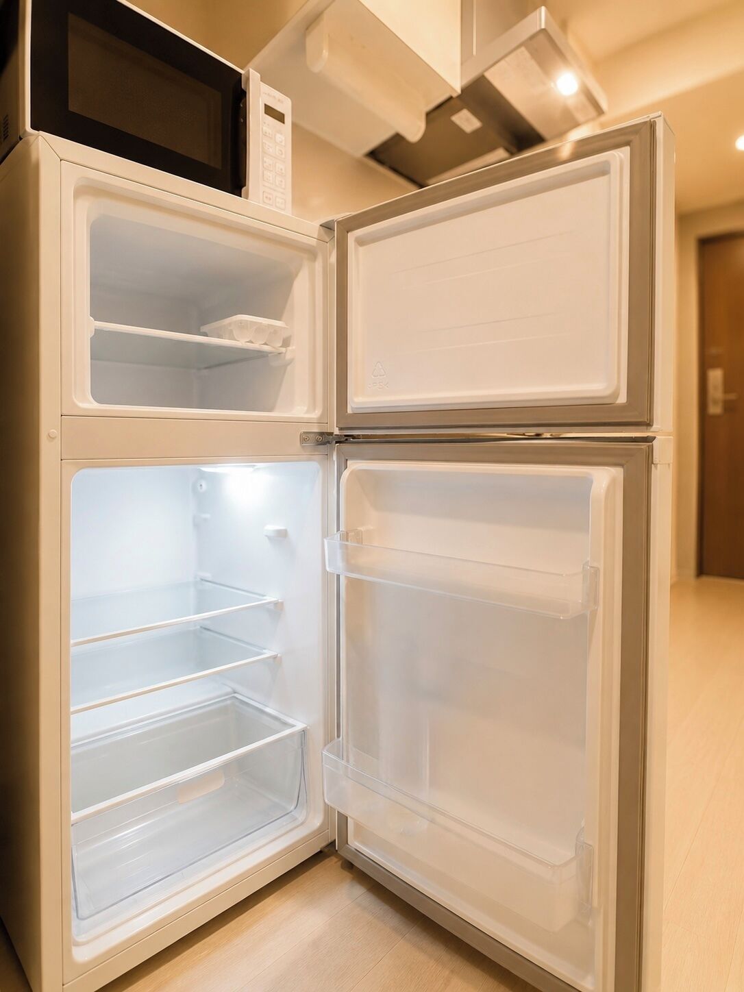 A double-door refrigerator with two shelves and a microwave above it.