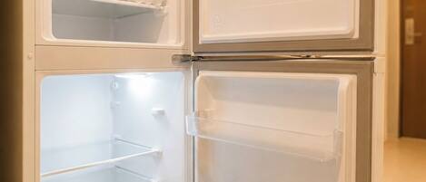 A double-door refrigerator with two shelves and a microwave above it.