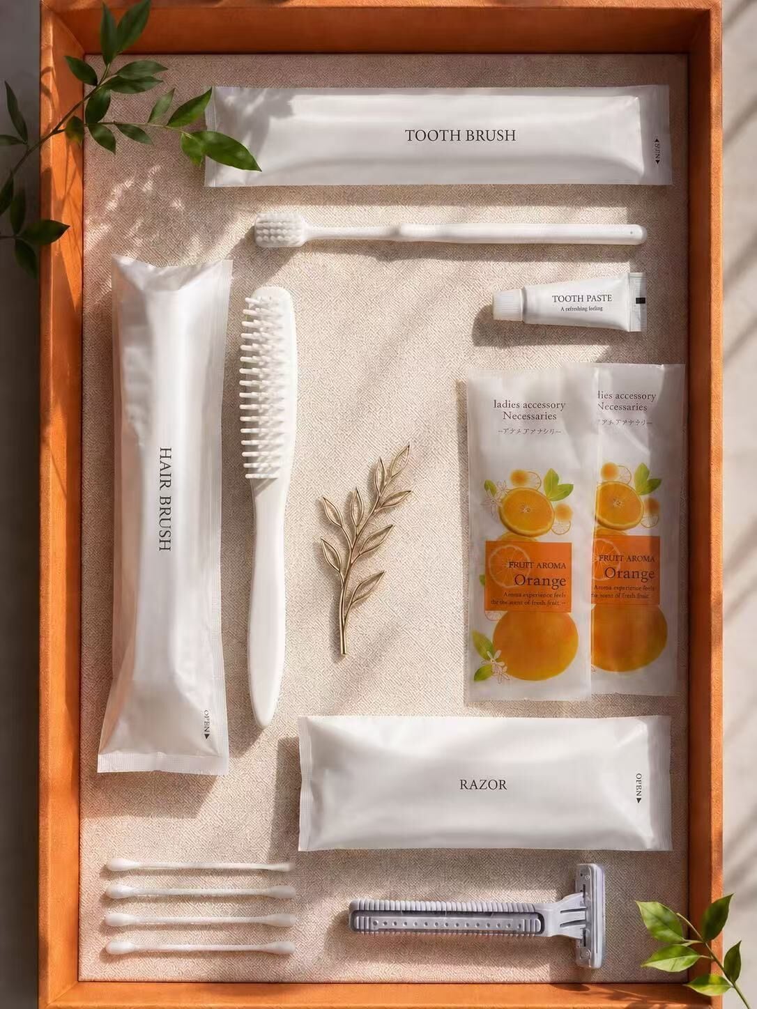 Un set de artículos de tocador ordenado en una caja de madera, con una toalla, cepillo de dientes, pasta dental, cepillo para el cabello, navaja y bastoncillos de algodón.