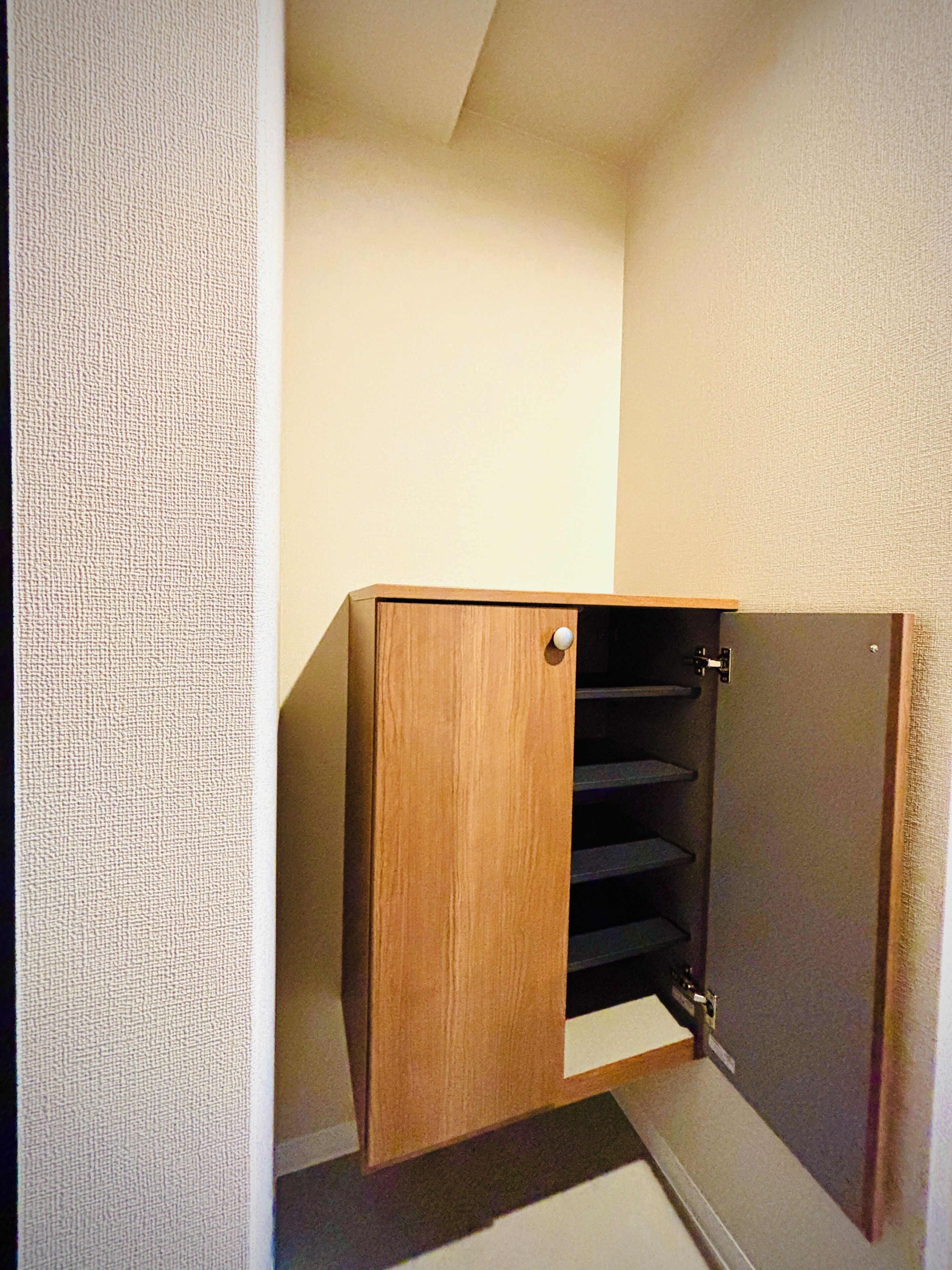 A wooden closet with a sliding door, built-in shelves, and a small step at the bottom.