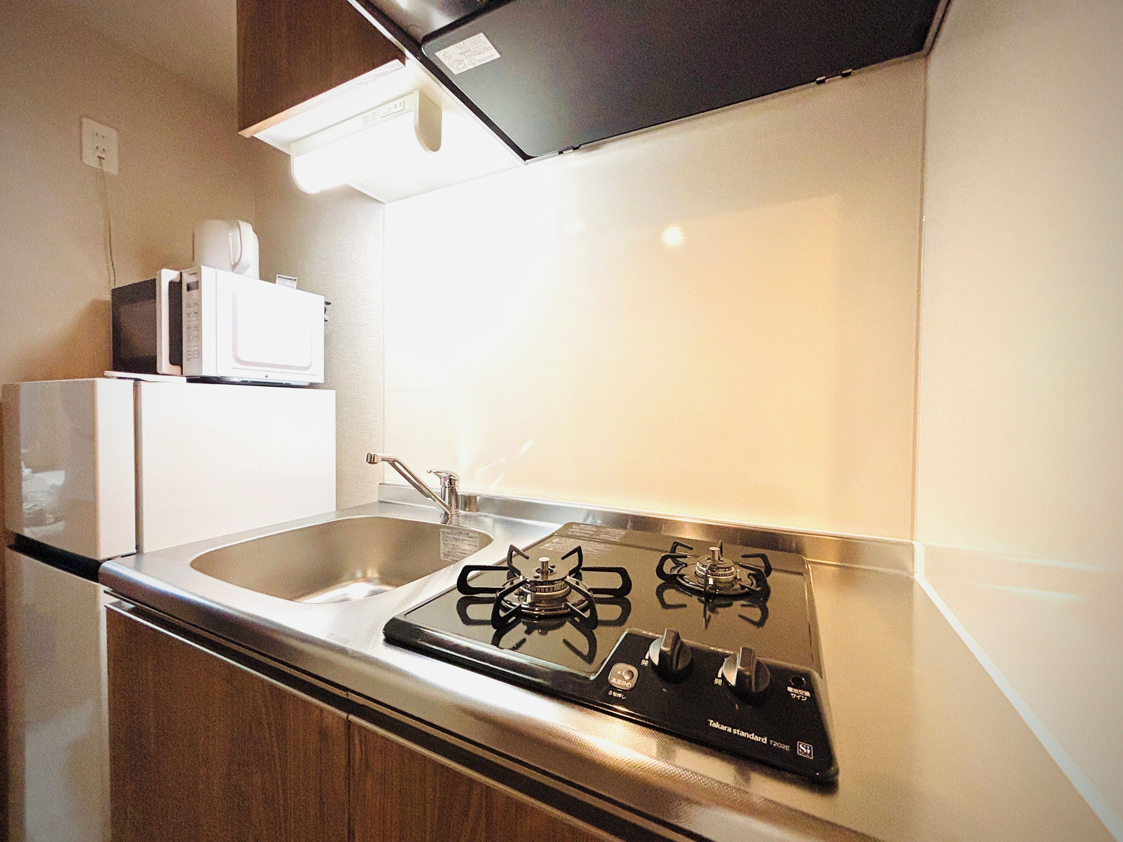 A kitchen with a gas stove, a sink, and a microwave.