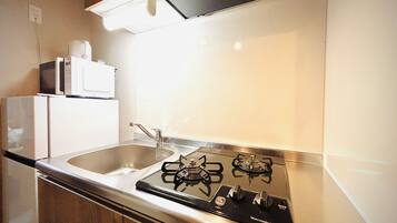 A kitchen with a gas stove, a sink, and a microwave.