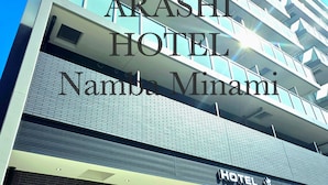 Un hôtel moderne dont le nom, « ARASHI HOTEL Namda Minami », est affiché en grand sur le bâtiment.